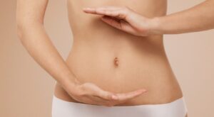 Nahaufnahme eines schlanken Bauches mit zwei Händen, die eine harmonische Balance symbolisieren – ein Zeichen für Darmgesundheit.