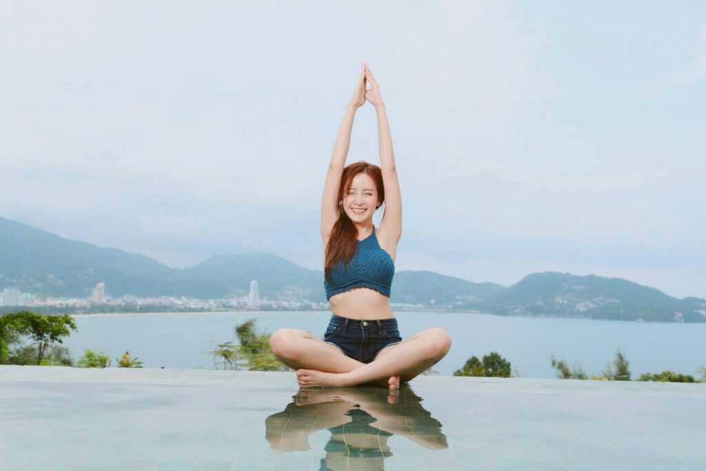 happy woman sitting in yoga pose close to a lake